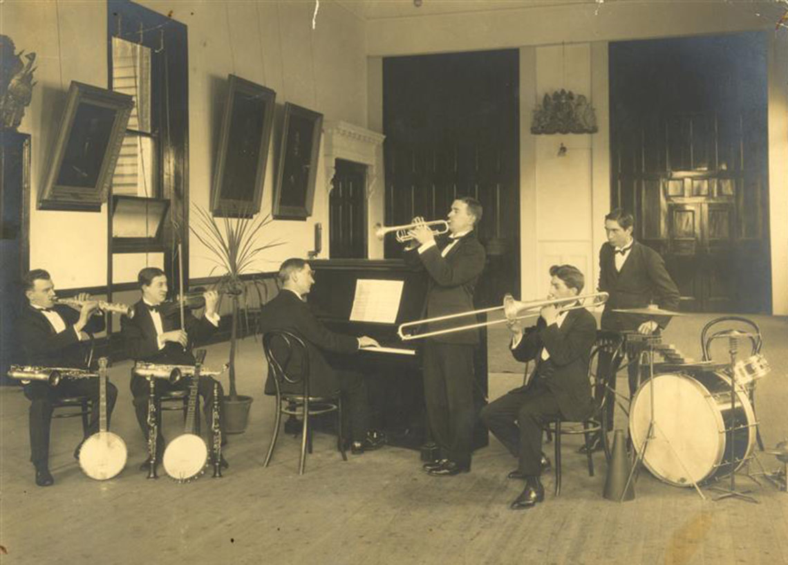 Six piece band wearing suits playing music in A Hall